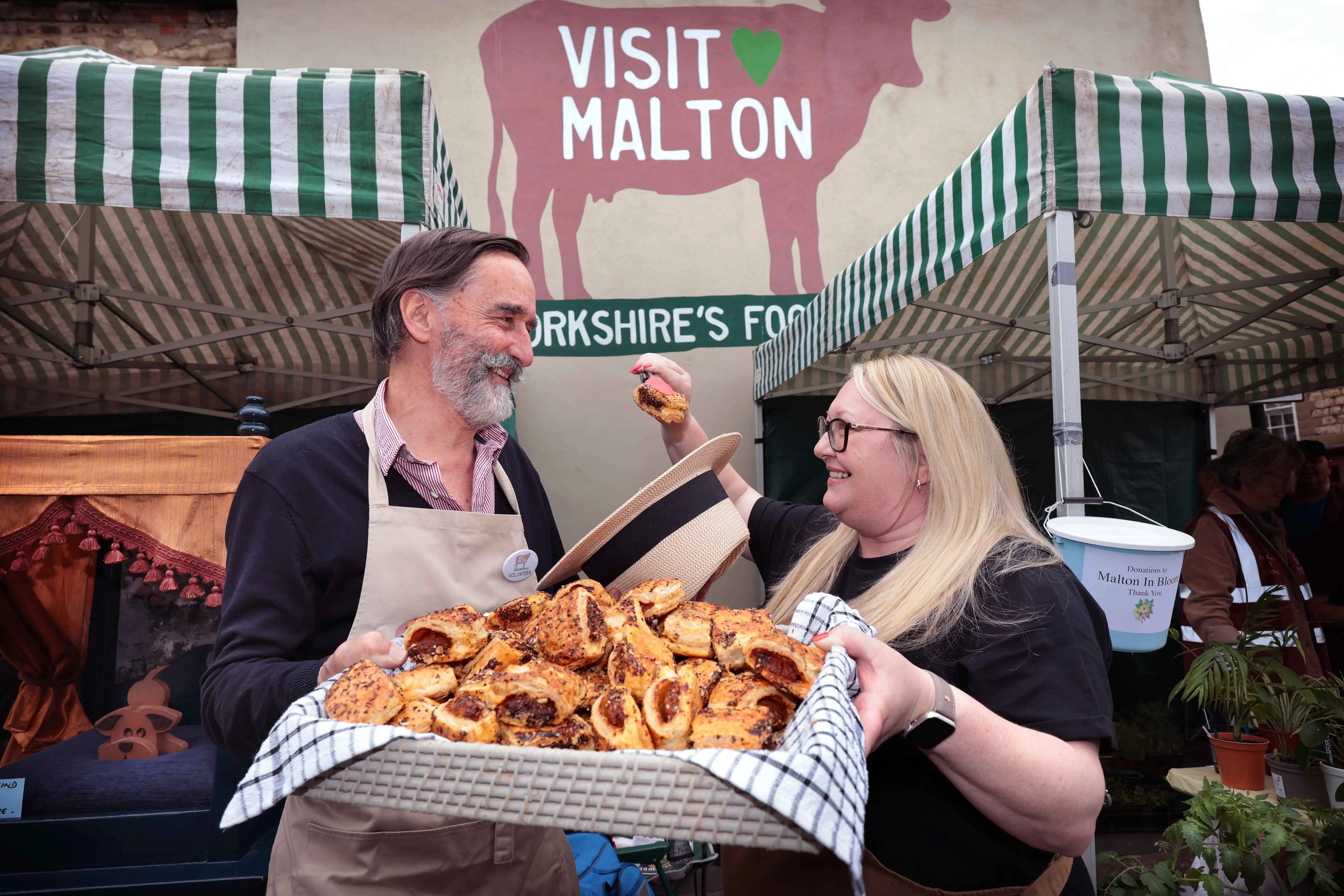man and woman presenting a large platter of food towards the camera